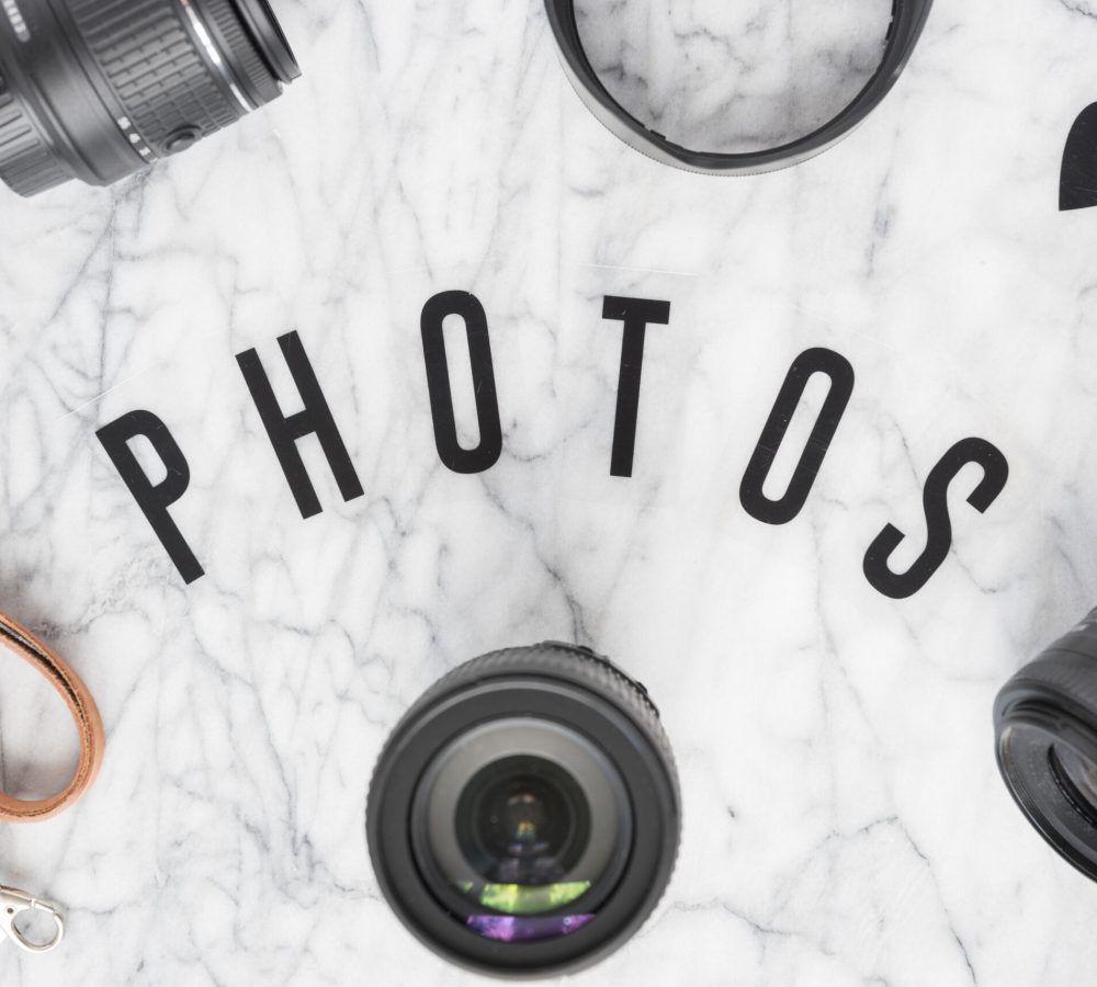 overhead-view-photos-text-surrounded-with-camera-accessories-heartshape-marble-background